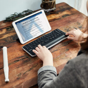 mulher utiliando a linha braille conectada a um tablet