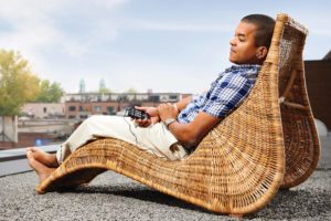 Homem sentado de forma relaxada na espreguiçadeira ouvindo seu Victor Reader Stream