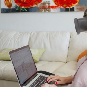 Mulher senatada no sofá digitando no laptop
